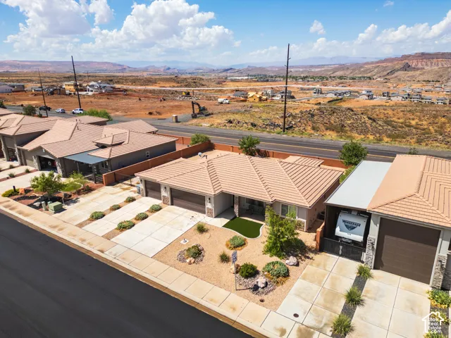Exterior residence featuring a tiled roof, attached two-car garage, and a desert-landscaped front yard with artificial turf
