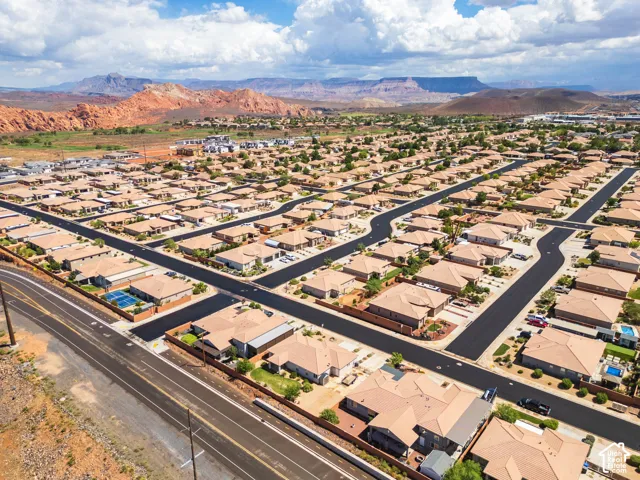 Residential community with consistent tan-colored roofing and a backdrop of red rock formations