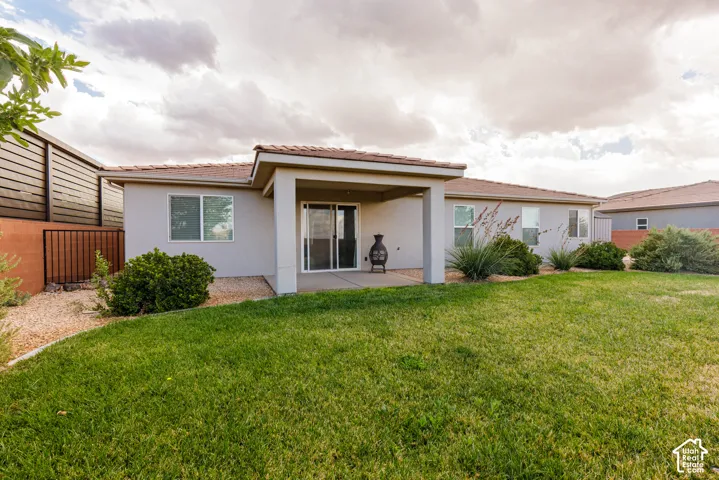 Expansive lawn area with mature landscaping, covered concrete patio, and stucco exterior