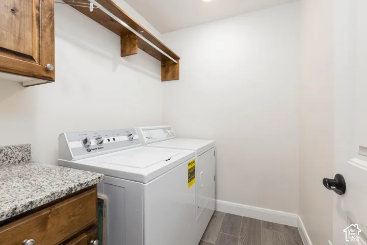 Laundry area featuring wood-finish cabinetry, granite-style countertop, and wood-finish flooring