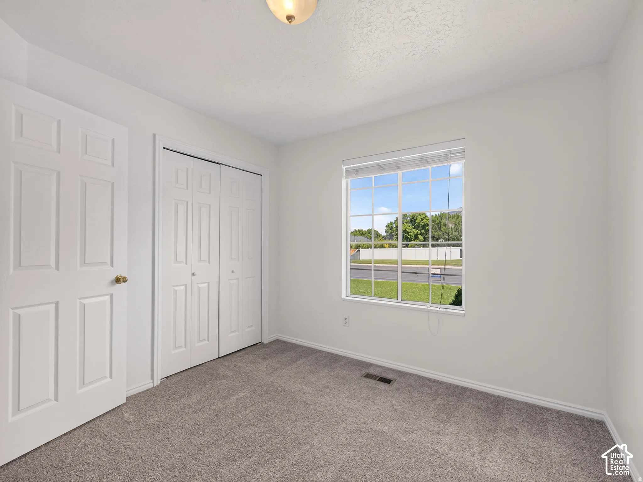 Neutral wall paint, carpet flooring, window with grid panes, bi-fold closet doors, and panel door