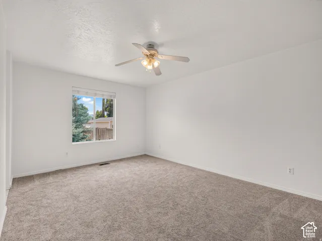 Neutral-toned carpeting, white painted walls, and a ceiling-mounted light fixture with fan