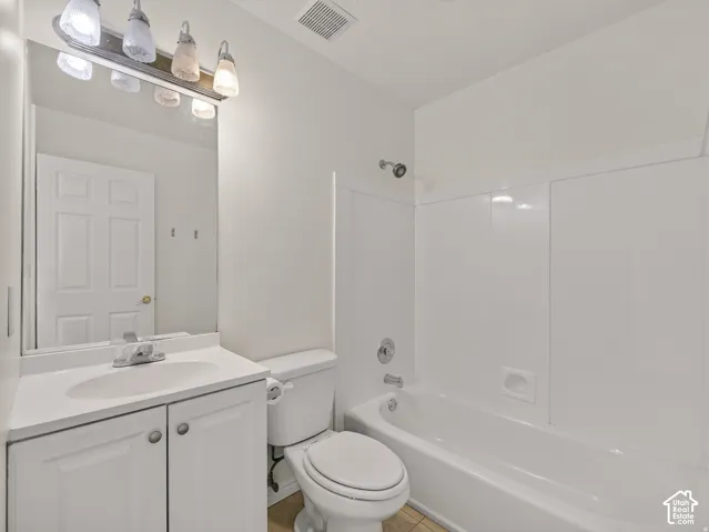 Bathroom featuring a vanity with a white countertop and integrated sink, a built-in bathtub with a shower, and a medicine cabinet with an attached light fixture