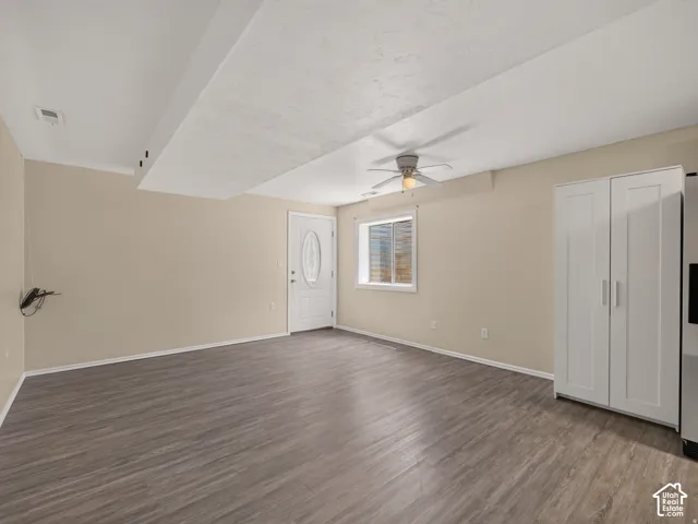Wood-finish flooring, recessed lighting, and a ceiling fan are featured in this space with a white paneled door with decorative glass