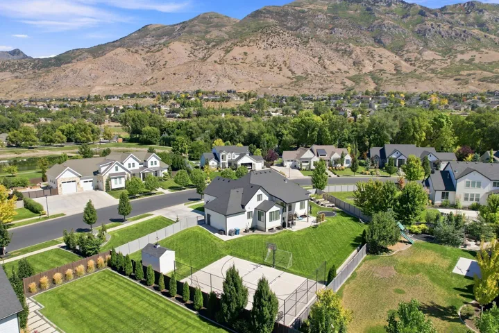 Expansive property featuring a manicured lawn, a built-in basketball court, and mature trees