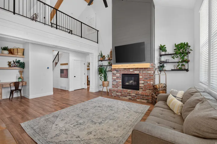 Loft-style living area featuring a brick fireplace, wood mantel, and wood-finish flooring