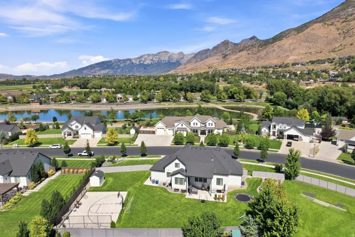 Expansive neighborhood featuring a large central pond, mature trees, and mountainous backdrop