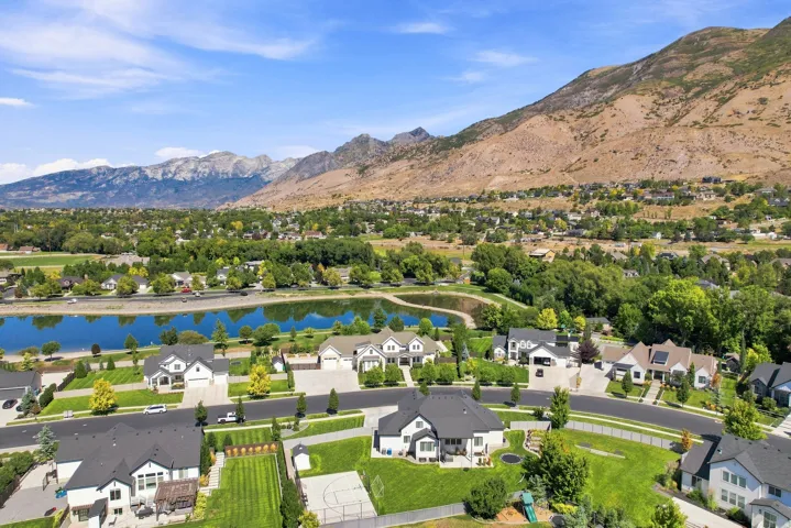 Residential development featuring a large water body, mature landscaping, and mountain backdrop
