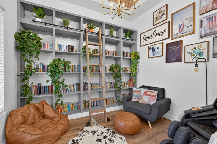 Custom built-in shelving with a rolling ladder, wood-finish flooring, and a contemporary light fixture