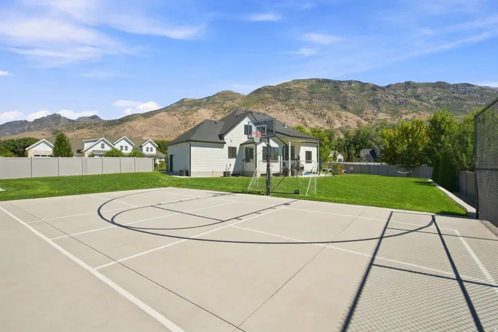 Expansive concrete sports court with defined markings, adjacent to a manicured lawn and a contemporary residence