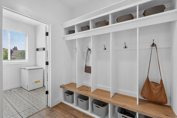Built-in hall tree with open shelving, wood-finish bench seating, and individual storage cubbies
