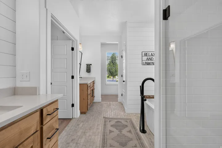 Double vanity with wood-finish cabinetry, light-toned countertops, and matte black hardware