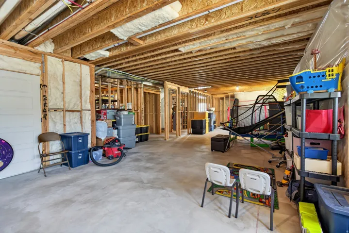 Unfinished basement featuring exposed wood joists, concrete flooring, spray foam insulation, and framed interior walls