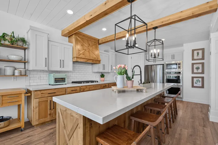 White shaker cabinetry with wood-finish lower cabinets, stone countertops, and subway tile backsplash