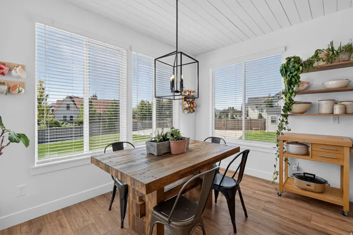 Wood-finish flooring, white shiplap ceiling, multiple windows with horizontal blinds, and a geometric pendant light fixture