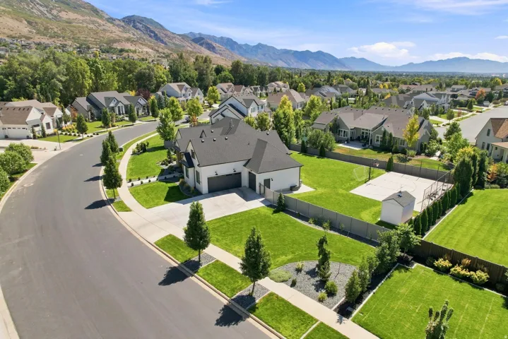 Contemporary-style residence with a dark gray roof, two-car garage, and a spacious backyard featuring a basketball court and storage shed