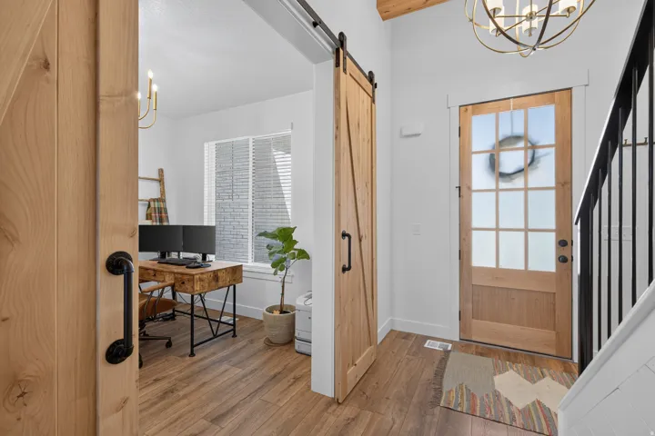 Wood-finish flooring throughout, barn door entry, and a frosted glass-panel entry door