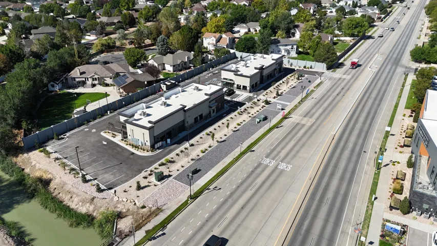 Two commercial buildings with contemporary design, extensive paved parking, and a landscaped median
