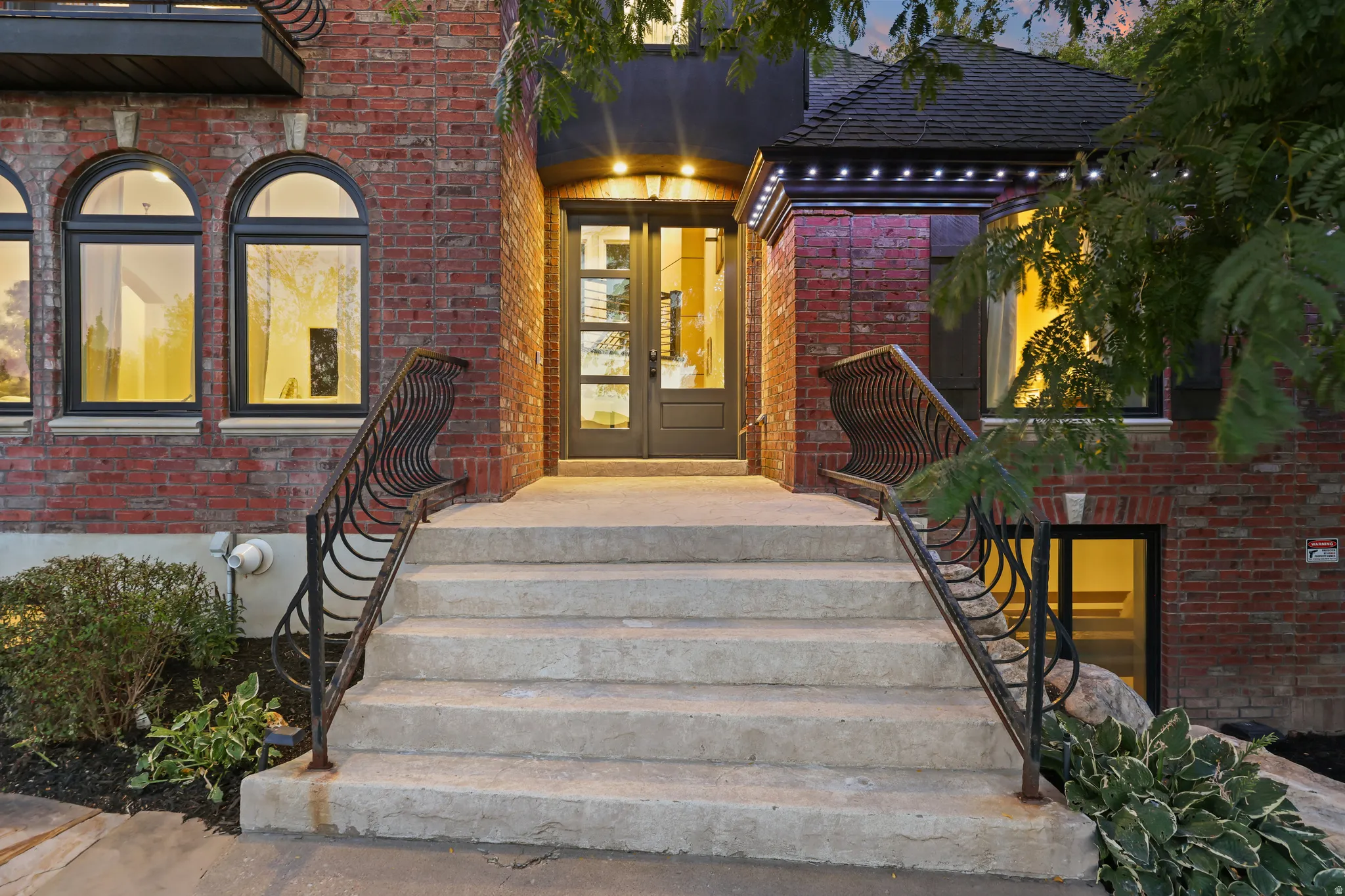 Brick exterior with arched windows, wrought iron railings, and a double-door entry