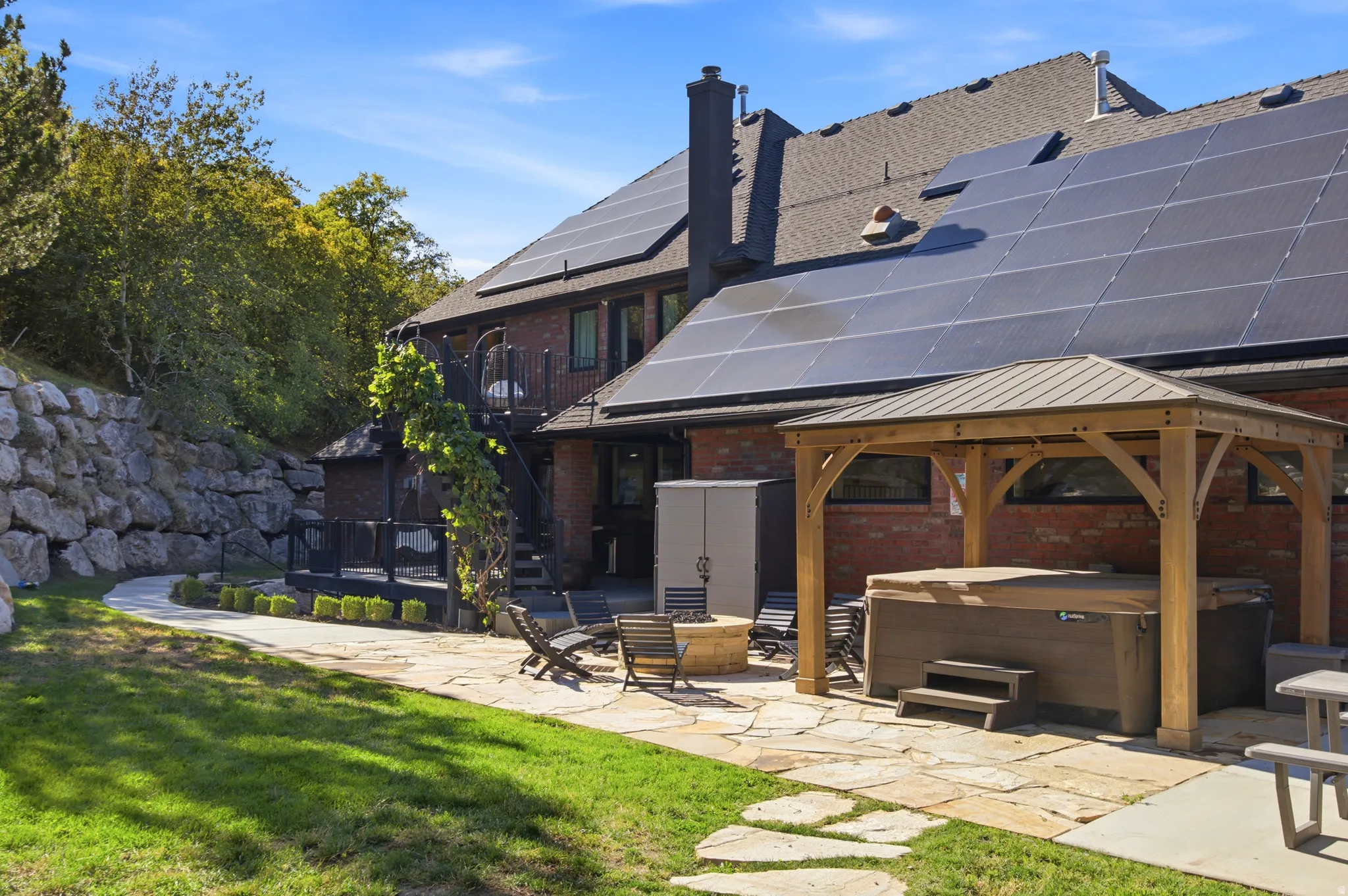 Brick exterior with solar panels, flagstone patio, and a wooden gazebo