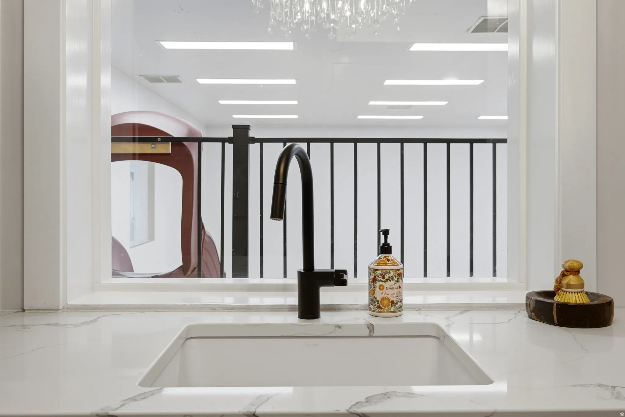 Undermount sink with a matte black faucet, set into a white countertop with gray veining