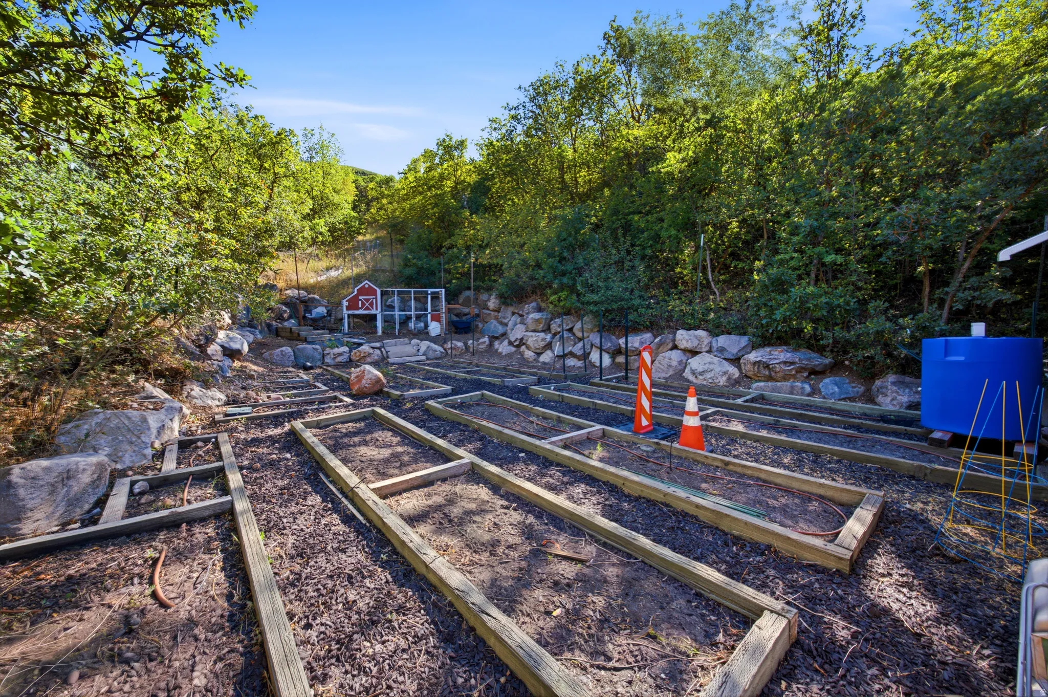 Terraced garden beds, a red barn-style shed, and a privacy fence