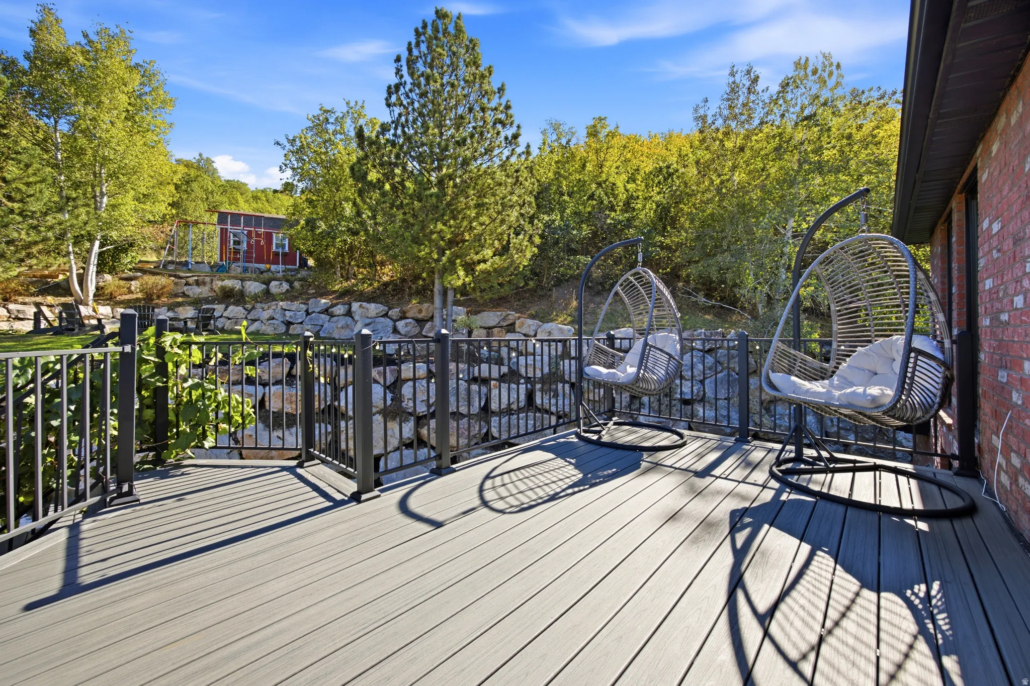 Expansive deck with wood-finish decking, black metal railing, and brick exterior