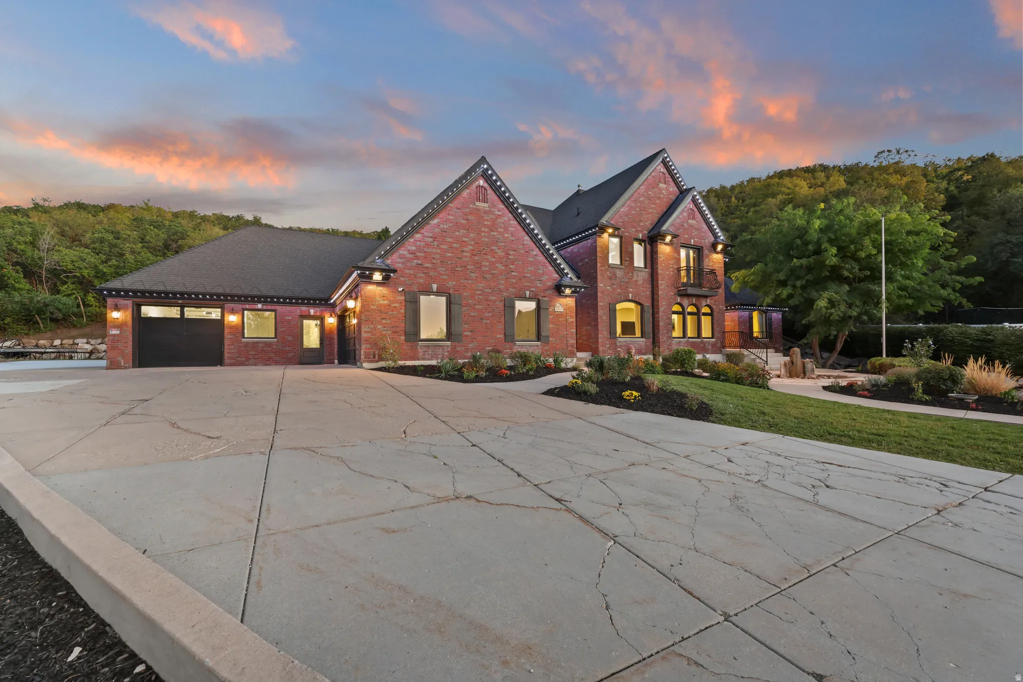 Brick exterior with dark shutters, attached two-car garage, arched entryways, and professional landscaping