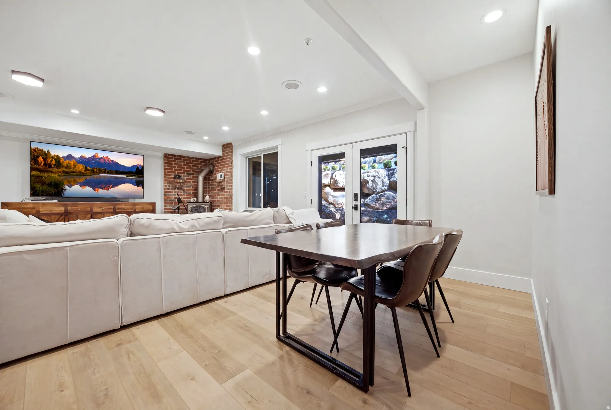 Recessed lighting, light wood-finish flooring, exposed brick wall, and a wood-burning stove
