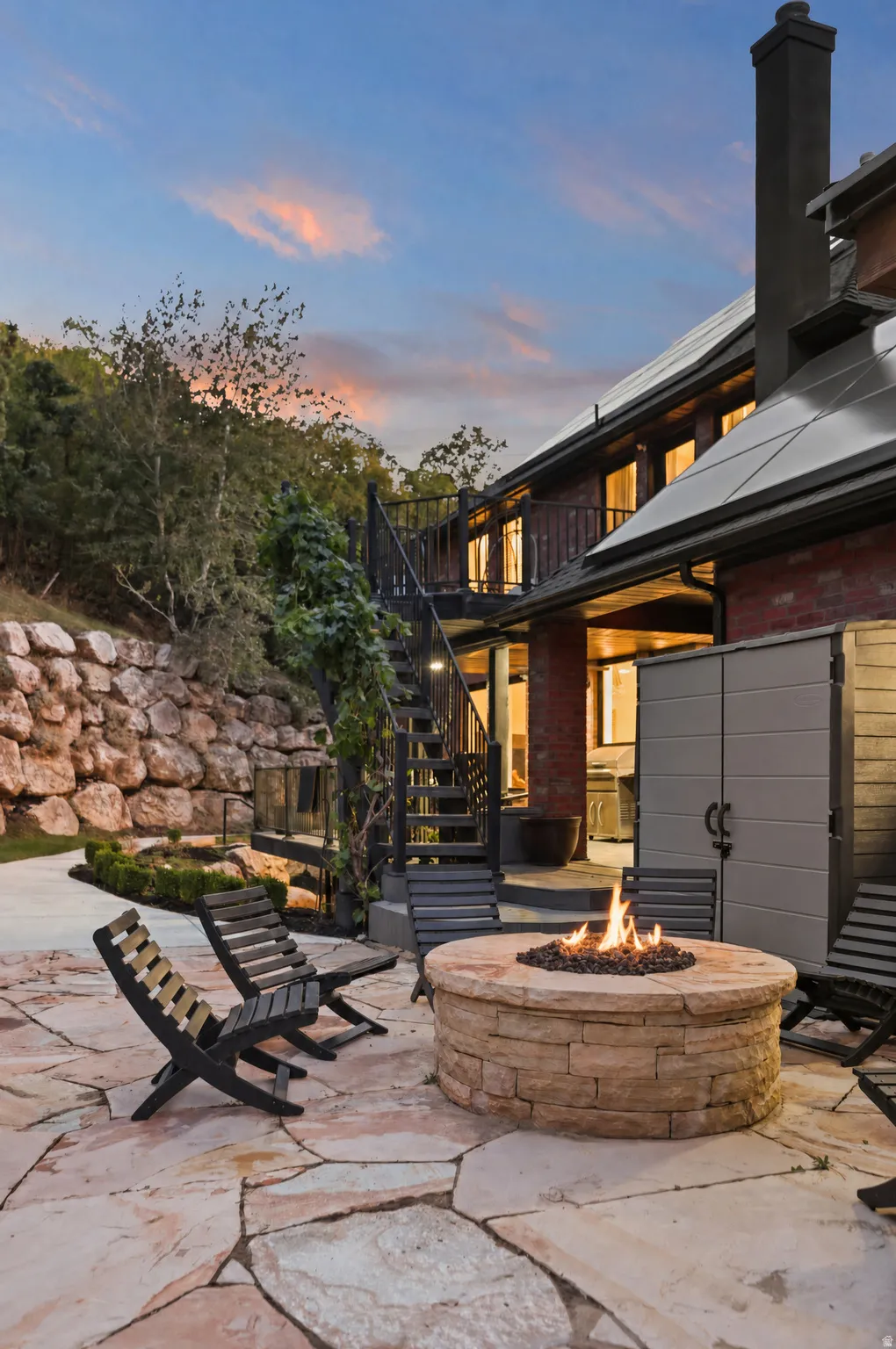 Expansive flagstone patio featuring a stone-clad fire pit