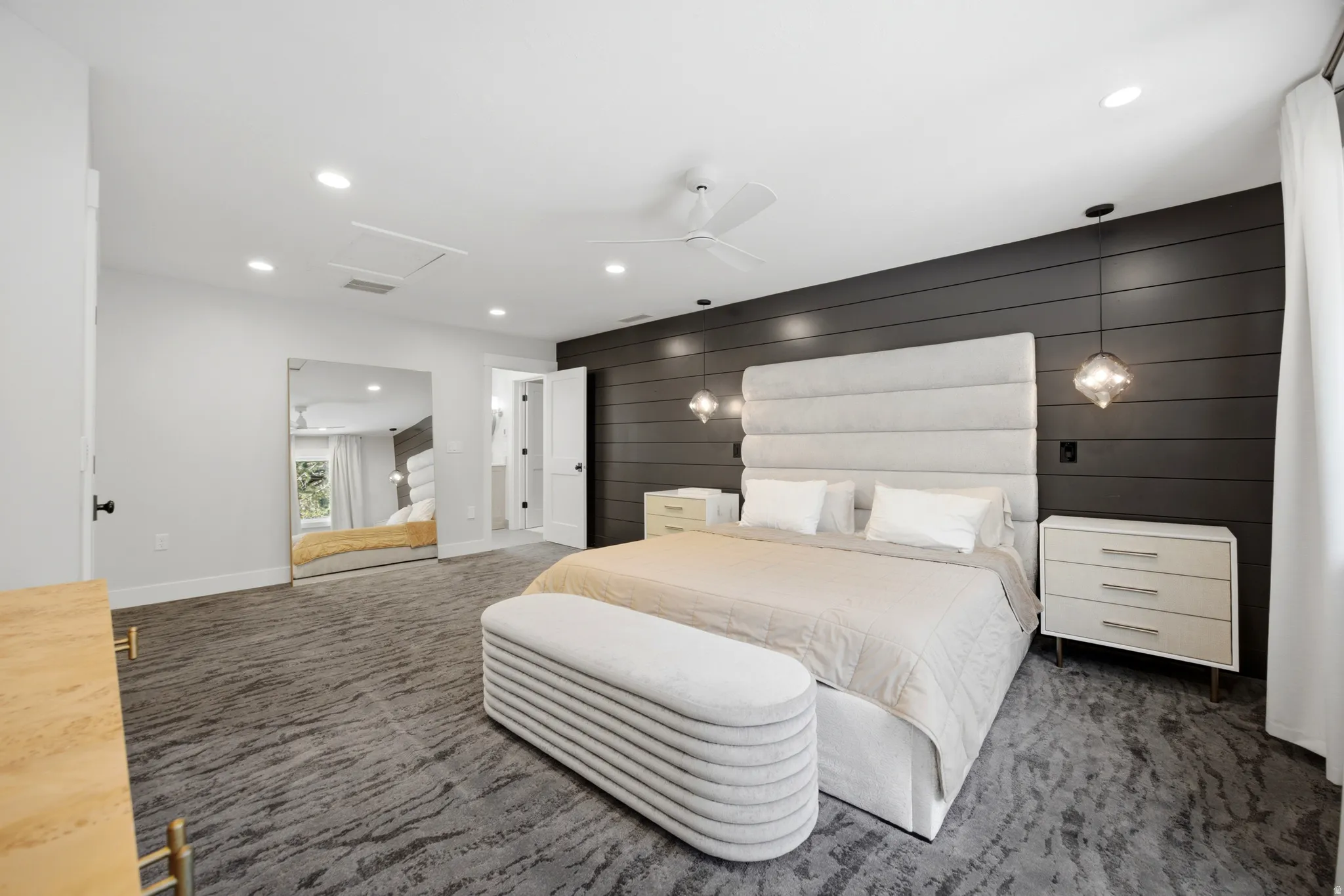 Patterned carpet flooring, recessed lighting, ceiling fan, dark shiplap accent wall, and built-in closet with mirrored doors