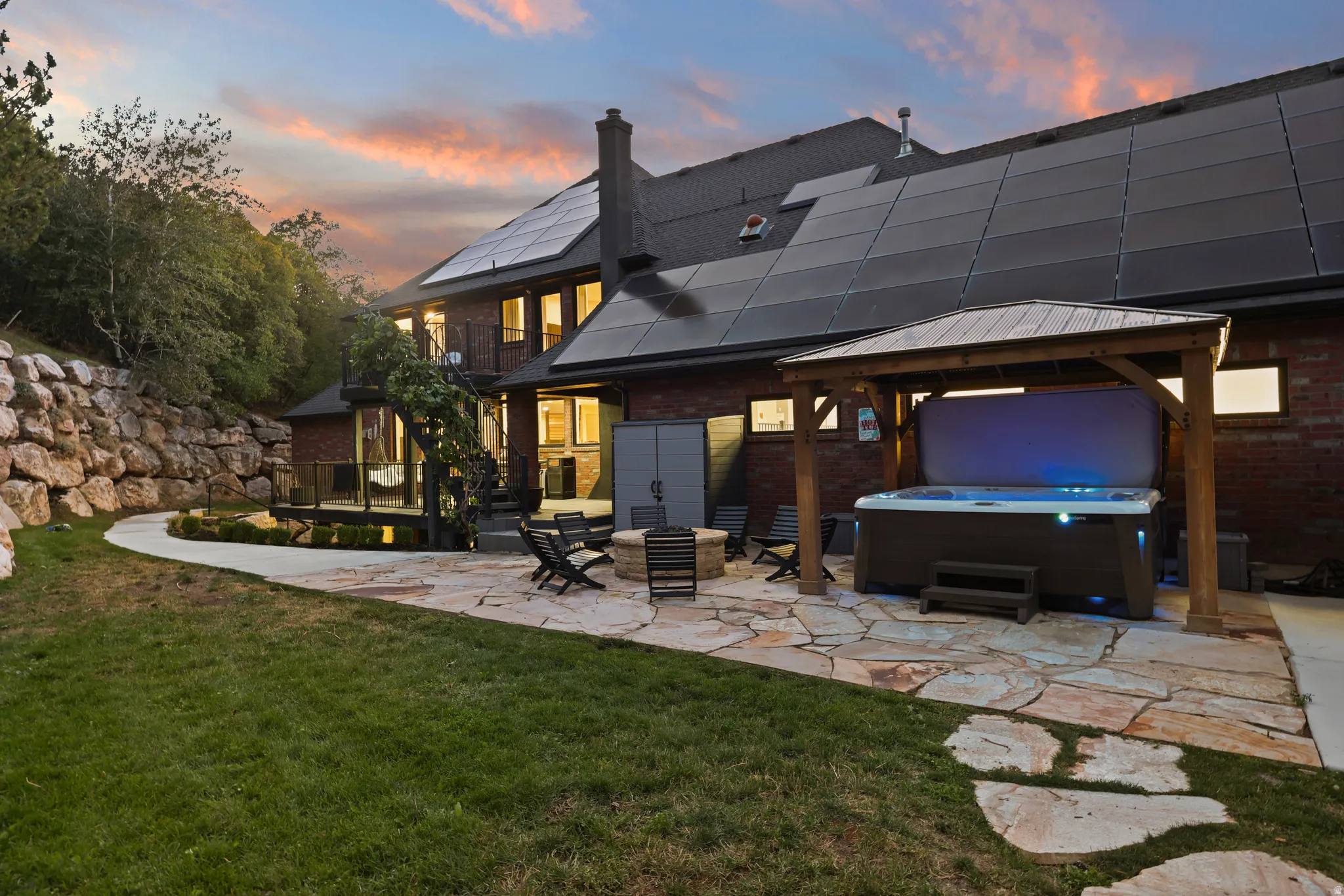Expansive stone patio featuring a hot tub with a wooden gazebo