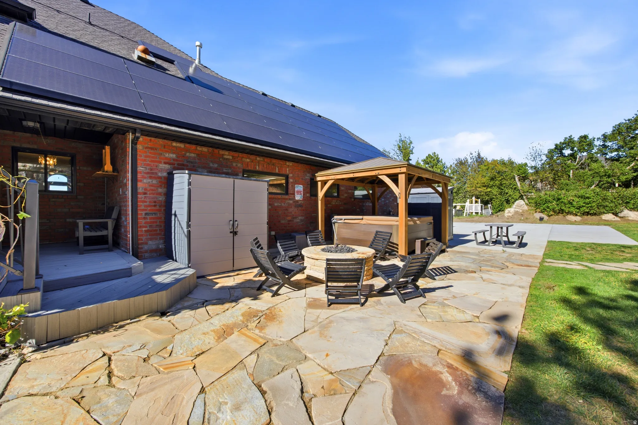 Stone patio with a fire pit, covered outdoor spa, and a concrete pad