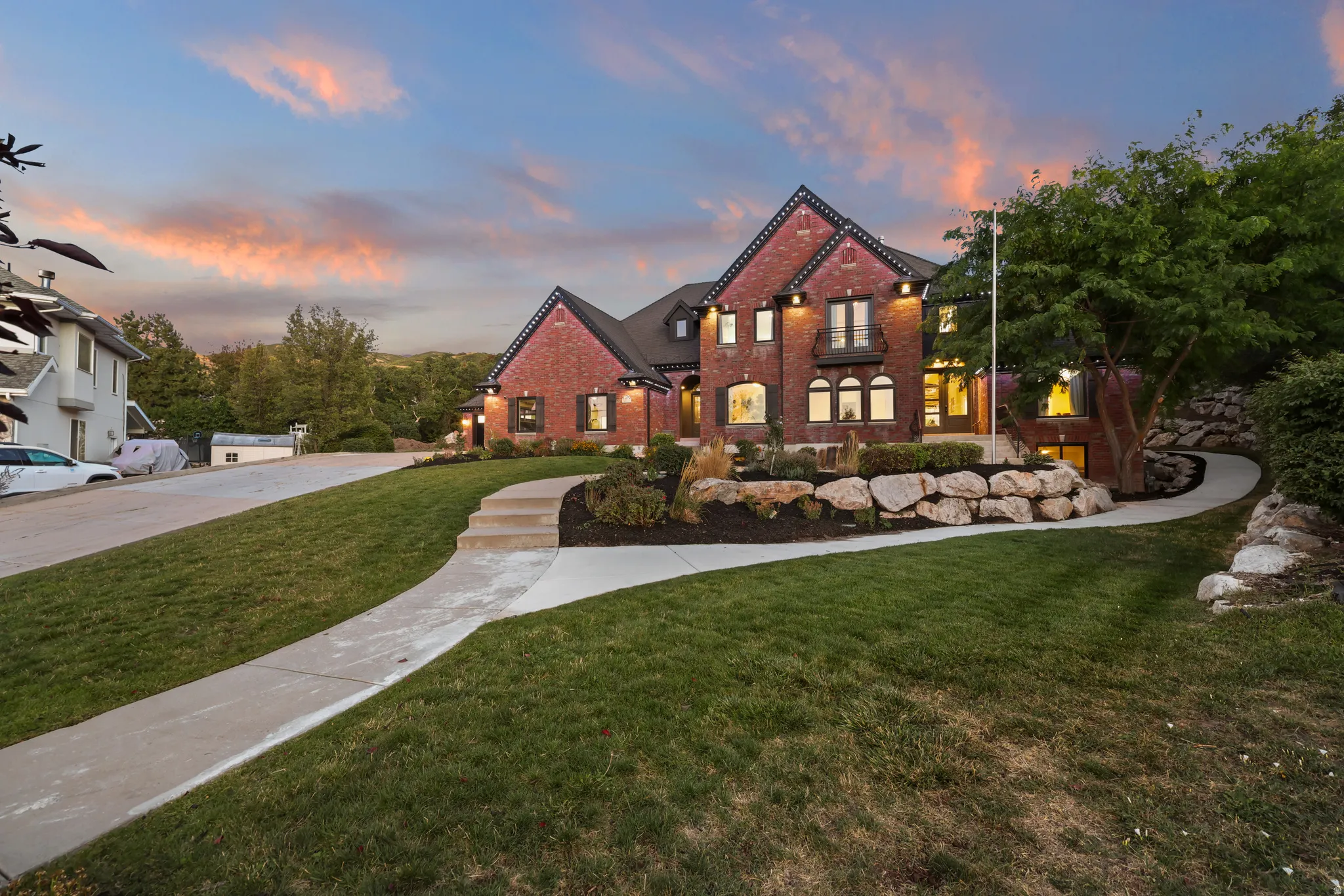 Brick exterior, multi-story structure, landscaped grounds with stone retaining walls, concrete walkway, and established plantings