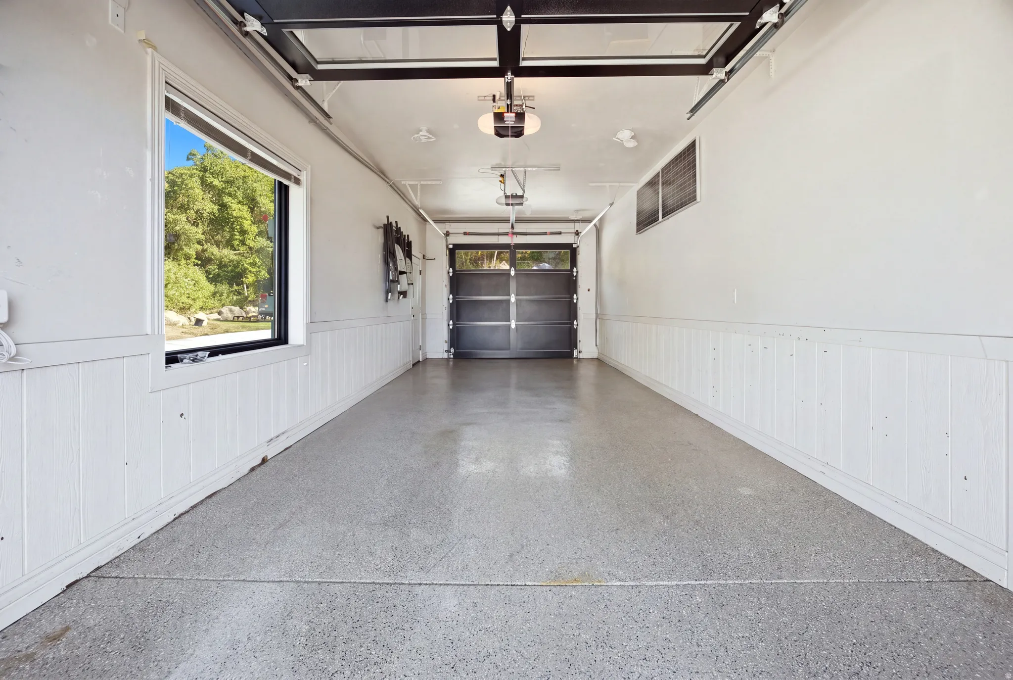 Garage with an epoxy floor finish, wainscoting, and a window