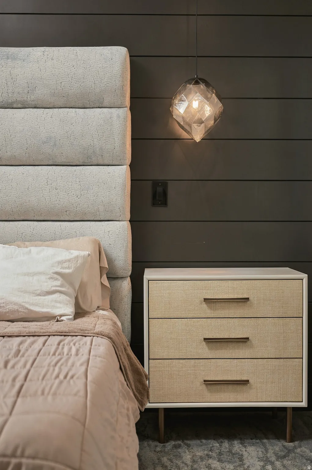 Stacked upholstered headboard, shiplap-style wall, and a geometric pendant light fixture