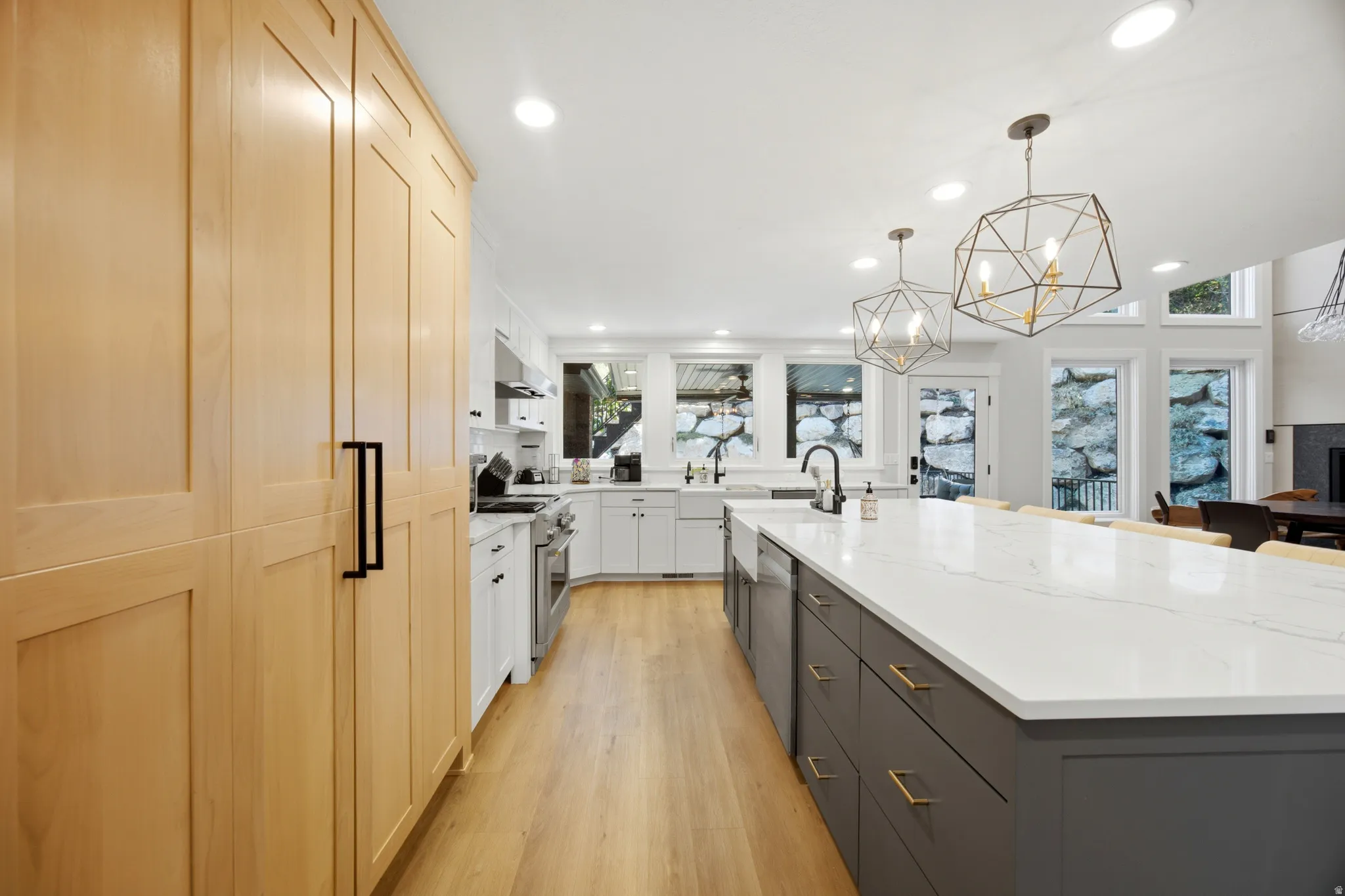 Spacious kitchen with a large central island, light wood-finish flooring, recessed lighting, and expansive windows