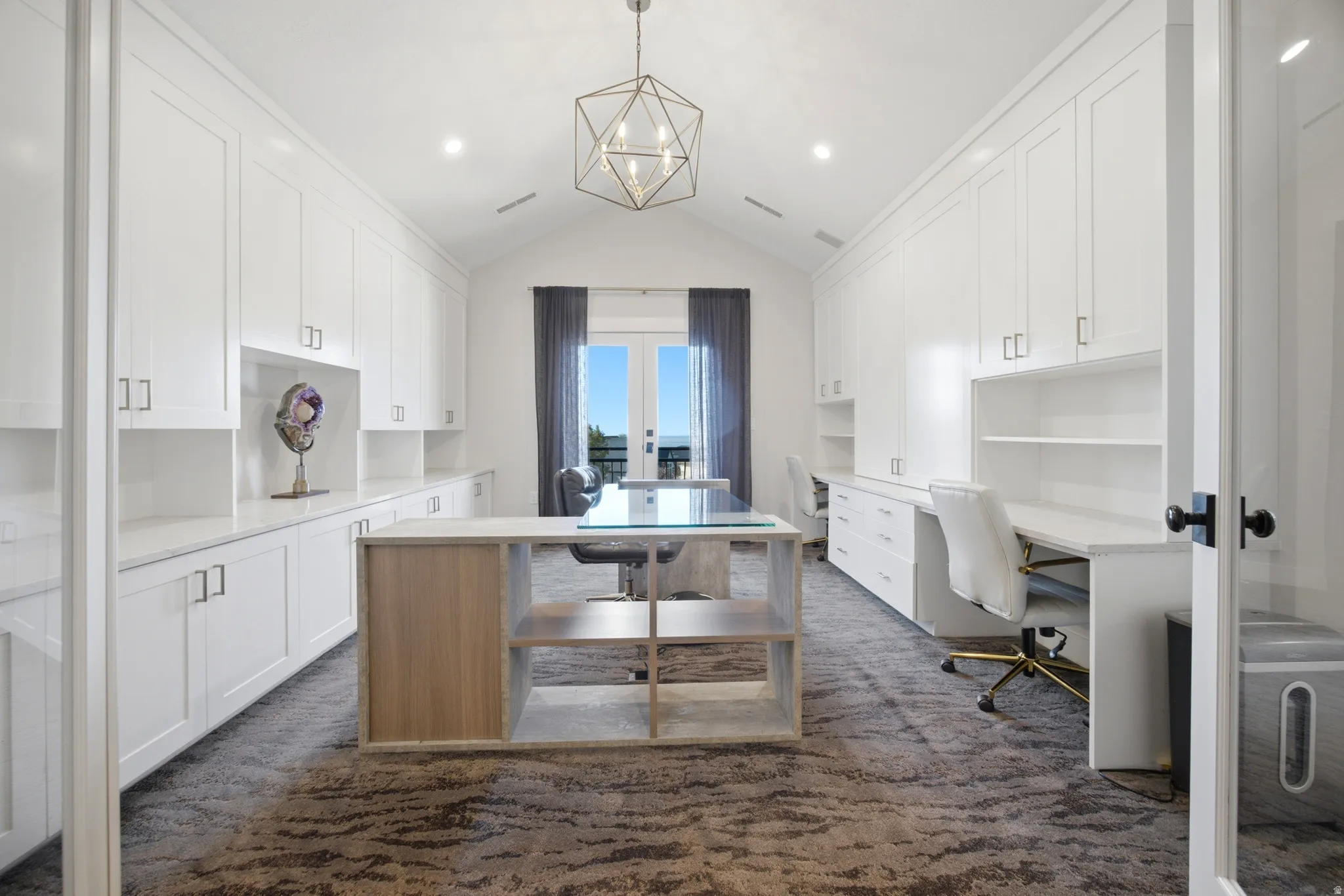 Vaulted ceilings, built-in cabinetry, dual workstations, central island with open shelving, and French doors