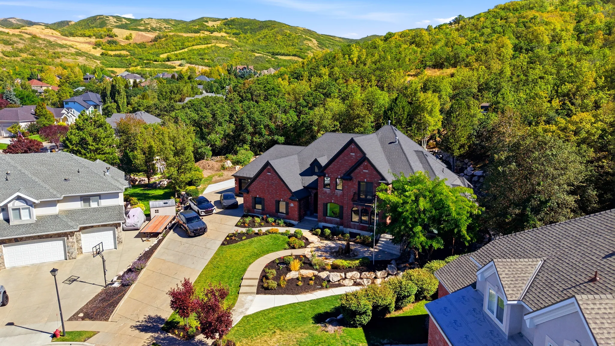 Red brick exterior, black shingles, multiple gables, and terraced landscaping