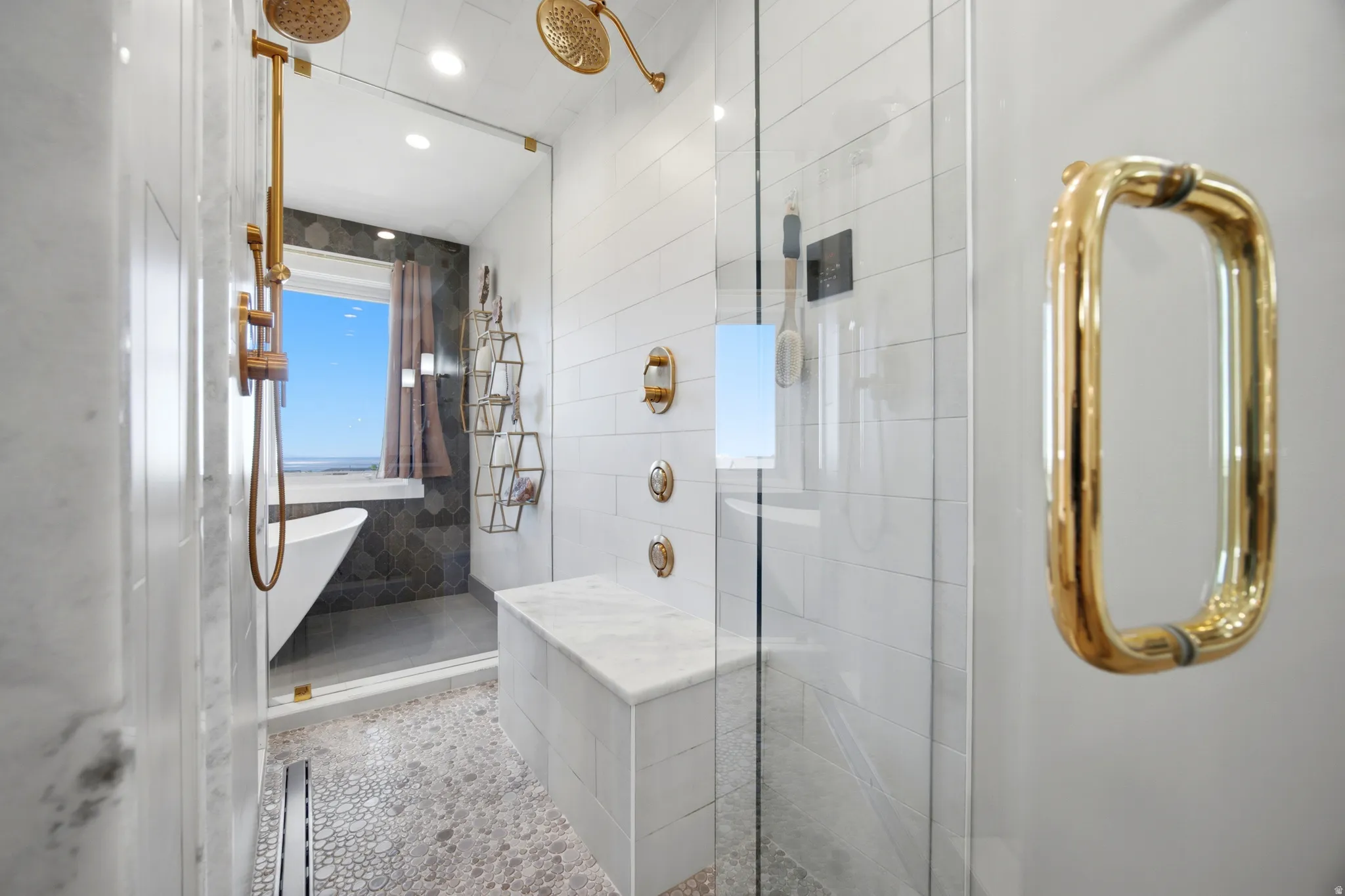 Glass-enclosed shower with pebble-finish flooring, a built-in bench, and dual shower heads