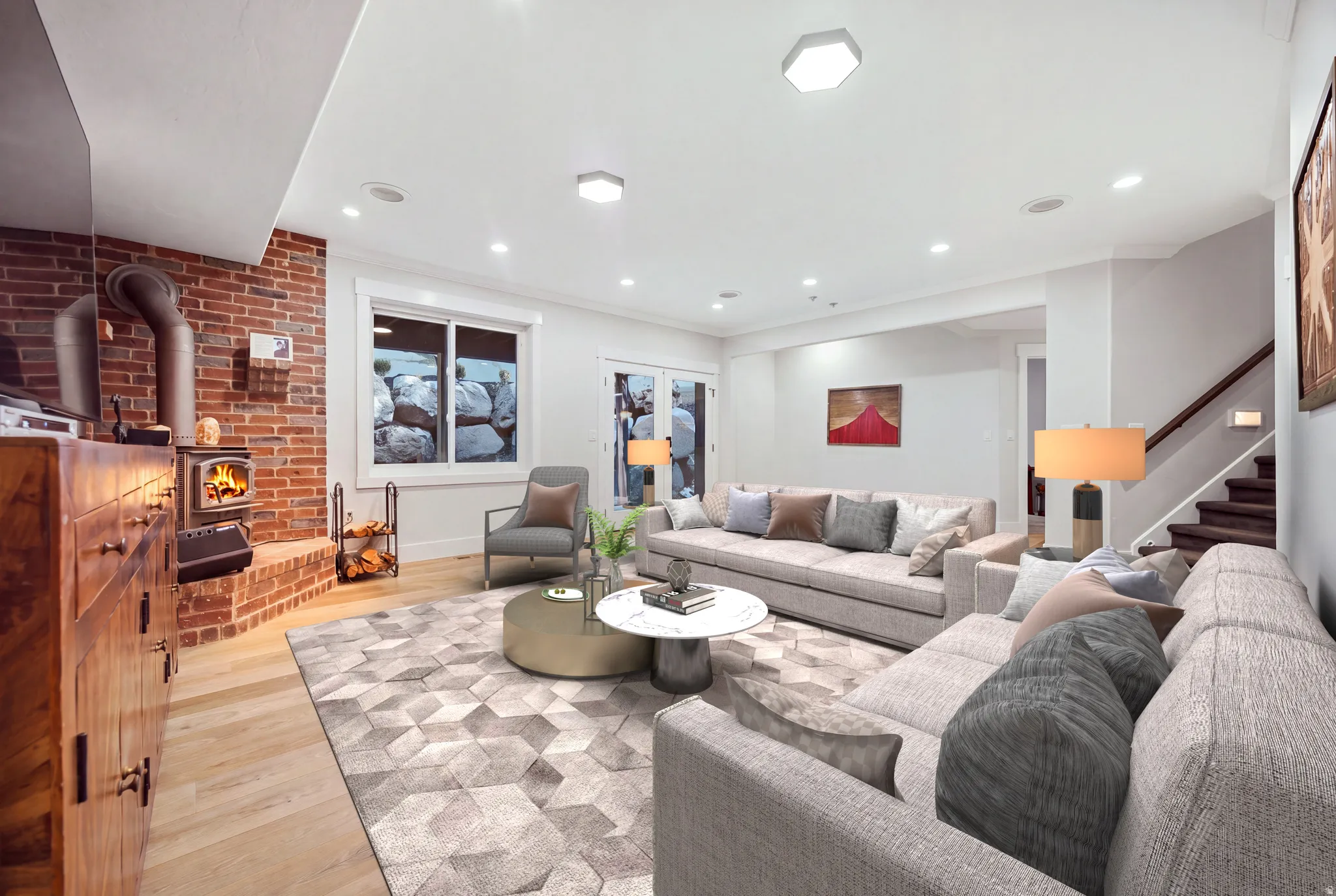 Exposed brick accent wall, built-in wood-burning stove, light wood-finish flooring, recessed ceiling lighting, and a staircase with wood treads