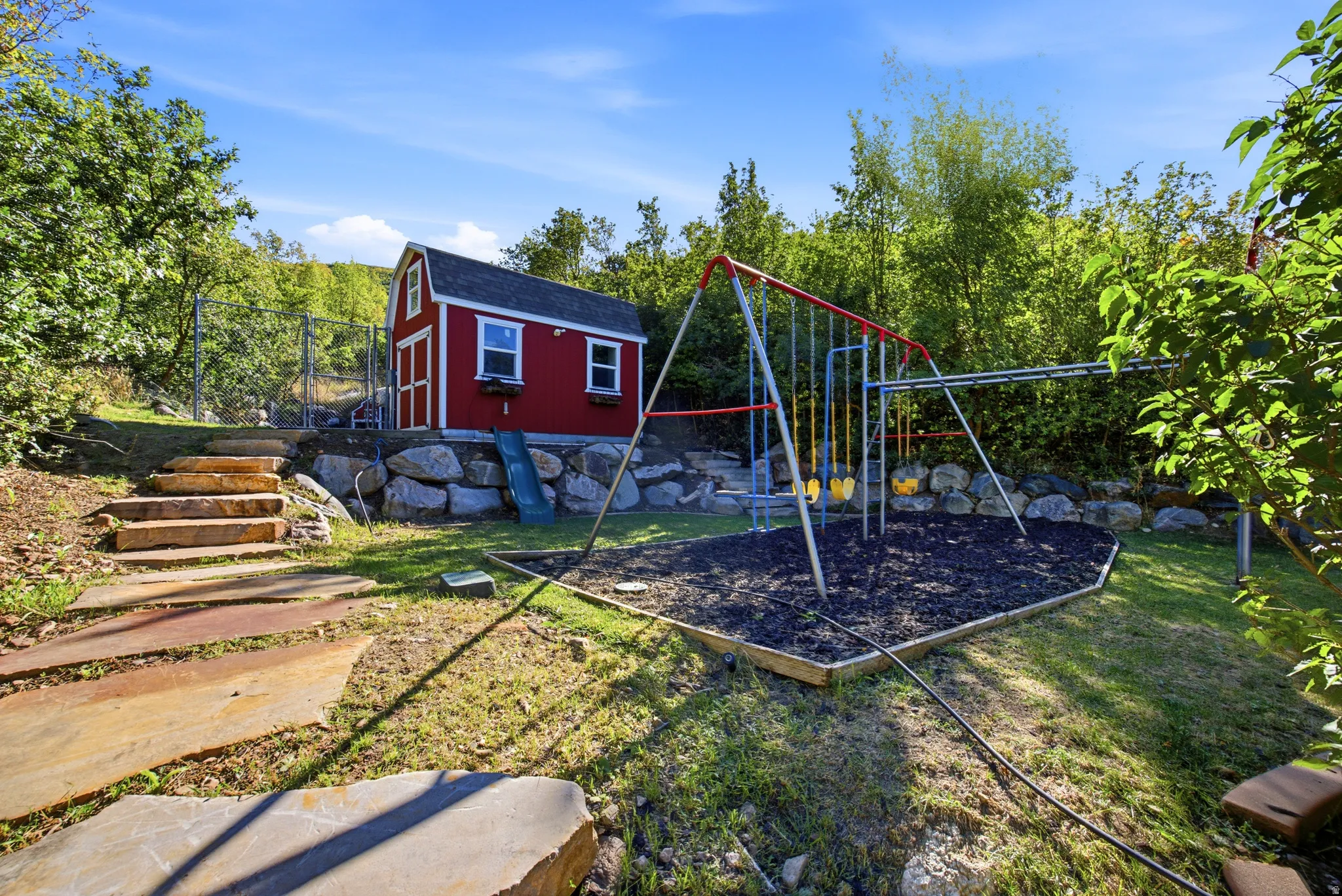 Expansive yard with a red storage shed, stone retaining wall, and a multi-level stone stairway