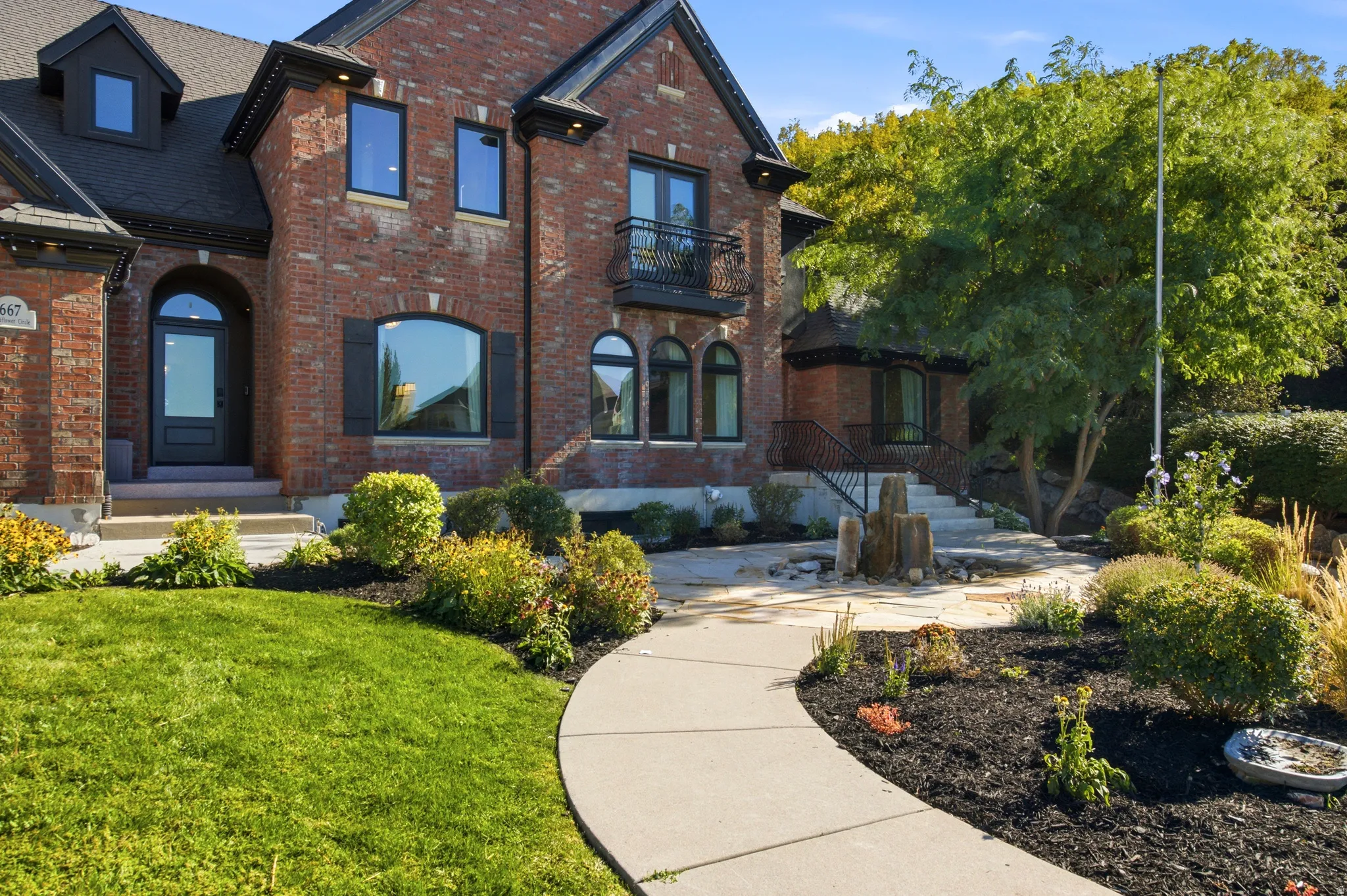 Brick exterior with dark trim windows, arched entryway, and a second-story balcony
