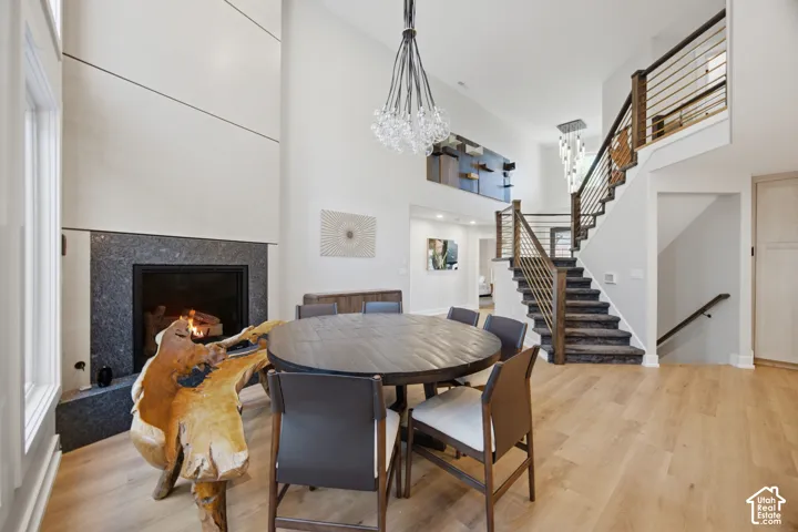 Vaulted ceilings, wood-finish flooring, a contemporary chandelier, a staircase with metal balusters, and a fireplace with a stone surround
