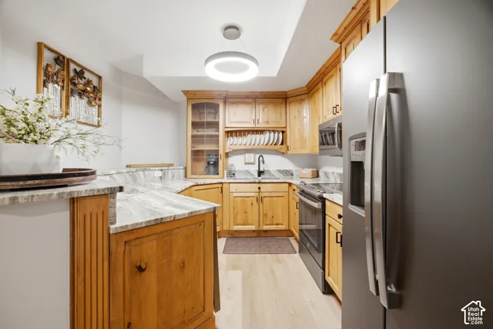 Kitchen featuring light wood cabinetry, light stone countertops, stainless steel appliances, and wood-finish flooring