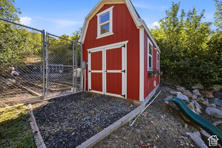 Red gambrel-style shed with white trim, dual doors, and side windows