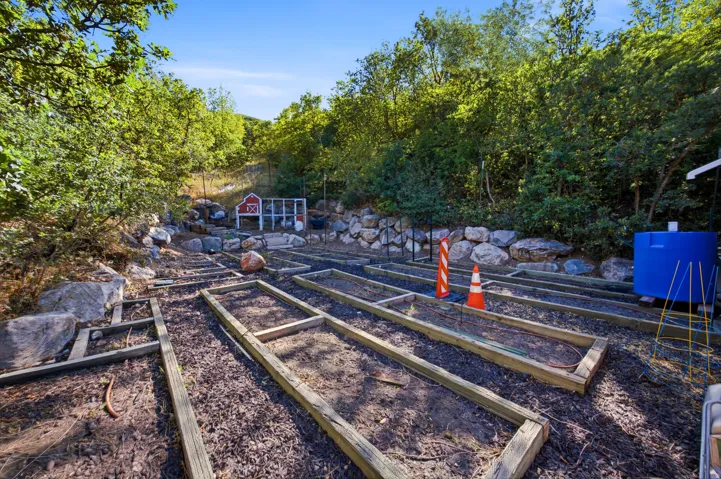 Terraced garden beds, a red barn-style shed, and a privacy fence