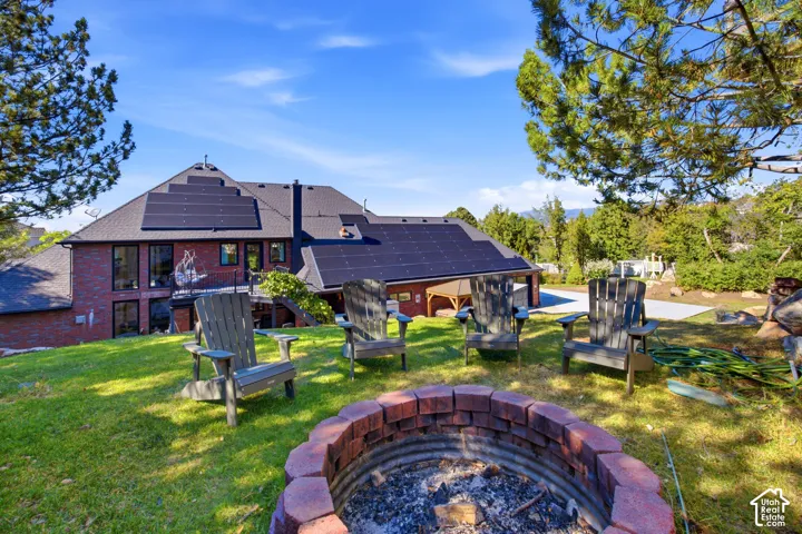 Expansive backyard with a brick-lined fire pit, mature trees, and a terraced lawn