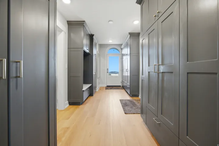 Hallway featuring built-in gray cabinetry, integrated bench seating, and light wood-finish flooring