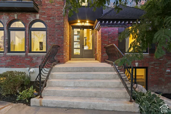 Brick exterior with arched windows, wrought iron railings, and a double-door entry